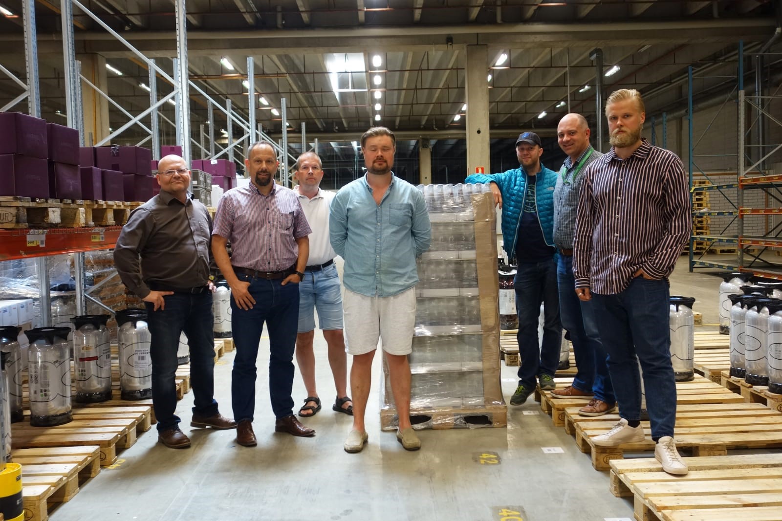 Seven men standing in a warehouse