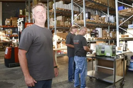 Smiling man next to two others in warehouse environment