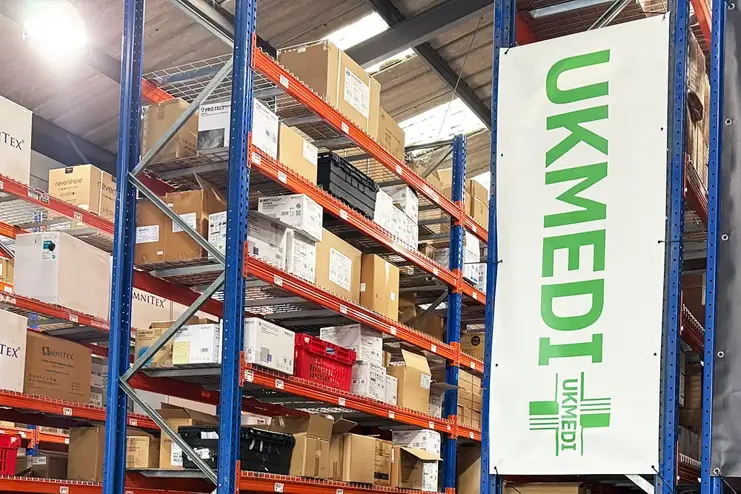 Lagerhyllor fyllda med kartonger och en vertikal UKMEDI-banderoll fäst på ställningen.