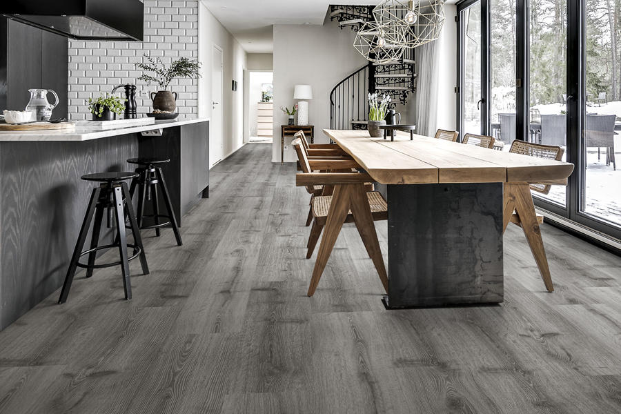 Modern kitchen and dining area with dark interior, wooden table and large windows