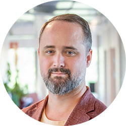 Professional headshot of a bearded man in an office environment