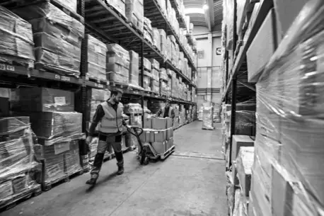 Man som drar en gaffeltruck i ett lager